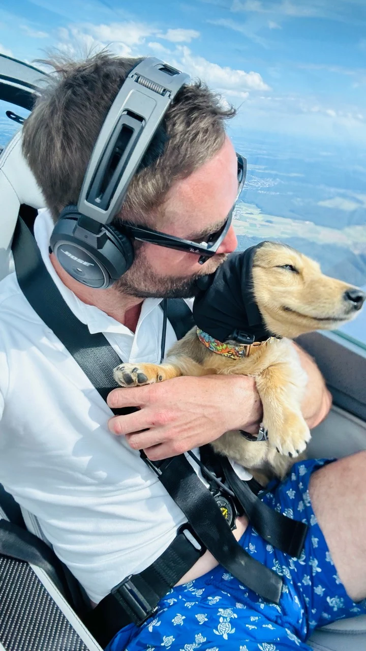 Sebastian kissing Rosi in the cockpit, both wearing aviation headsets
